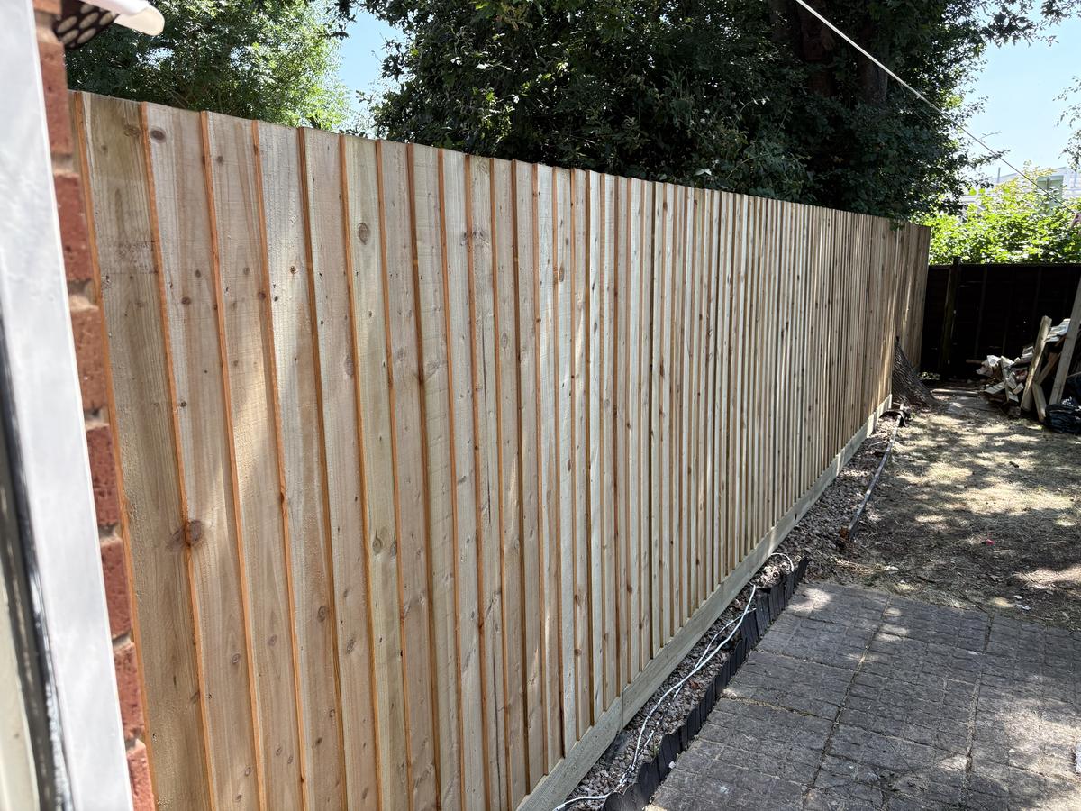 Long feather-edge fence along a patio