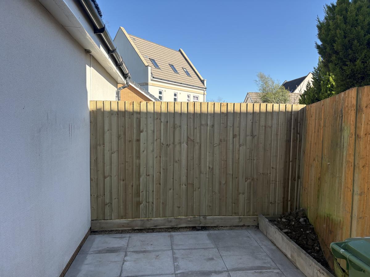 Courtyard with new feather-edge fence, gravel board and a sleeper-edged bed